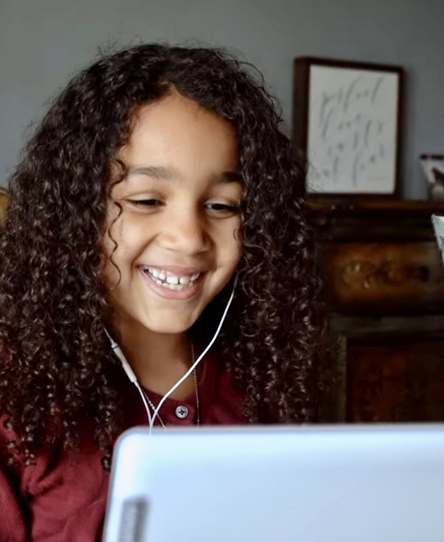 A smiling student wearing earbuds during a live online class