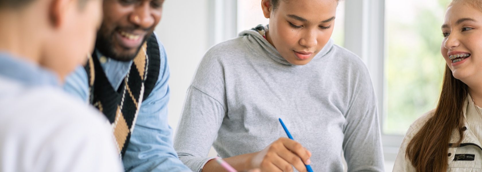A tutor working with two students at a table