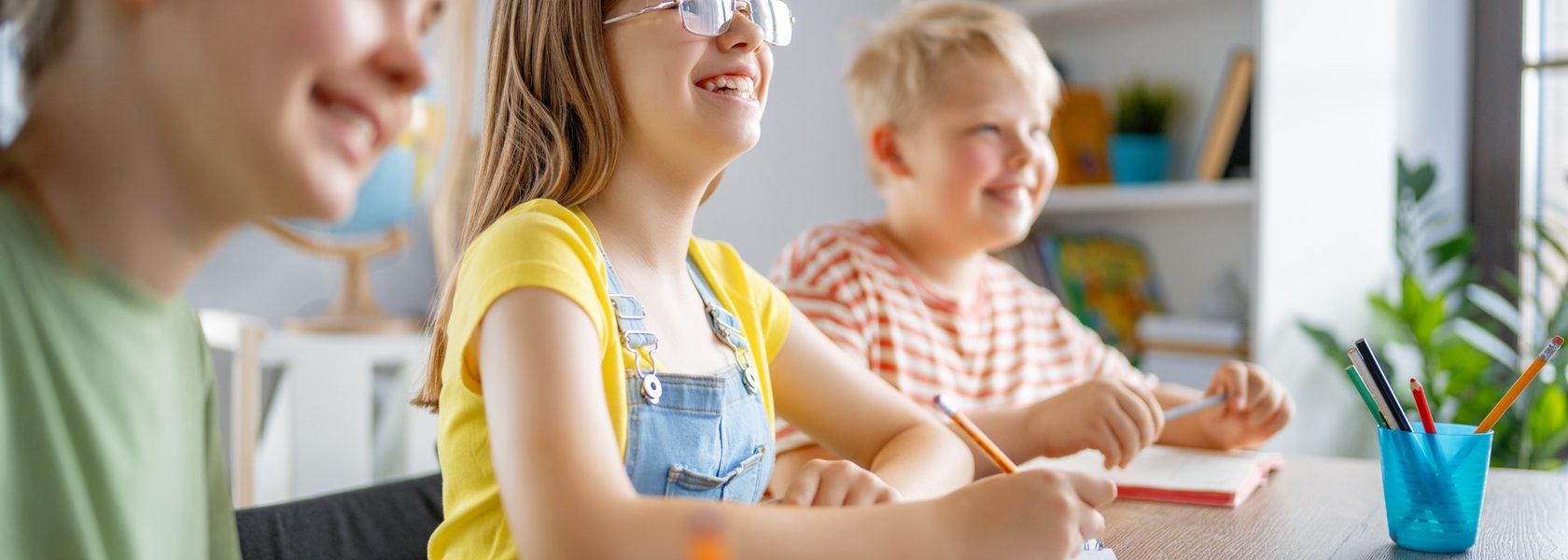 Children smiling while working together at a classroom table