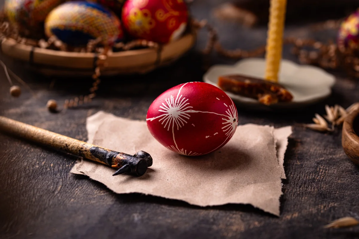 Hand-decorated red egg beside a beeswax candle, a traditional sign of Pascha and Orthodox Easter