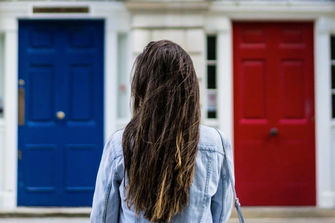 Young woman standing before a blue door and a red door, choosing between Mary and Martha learning