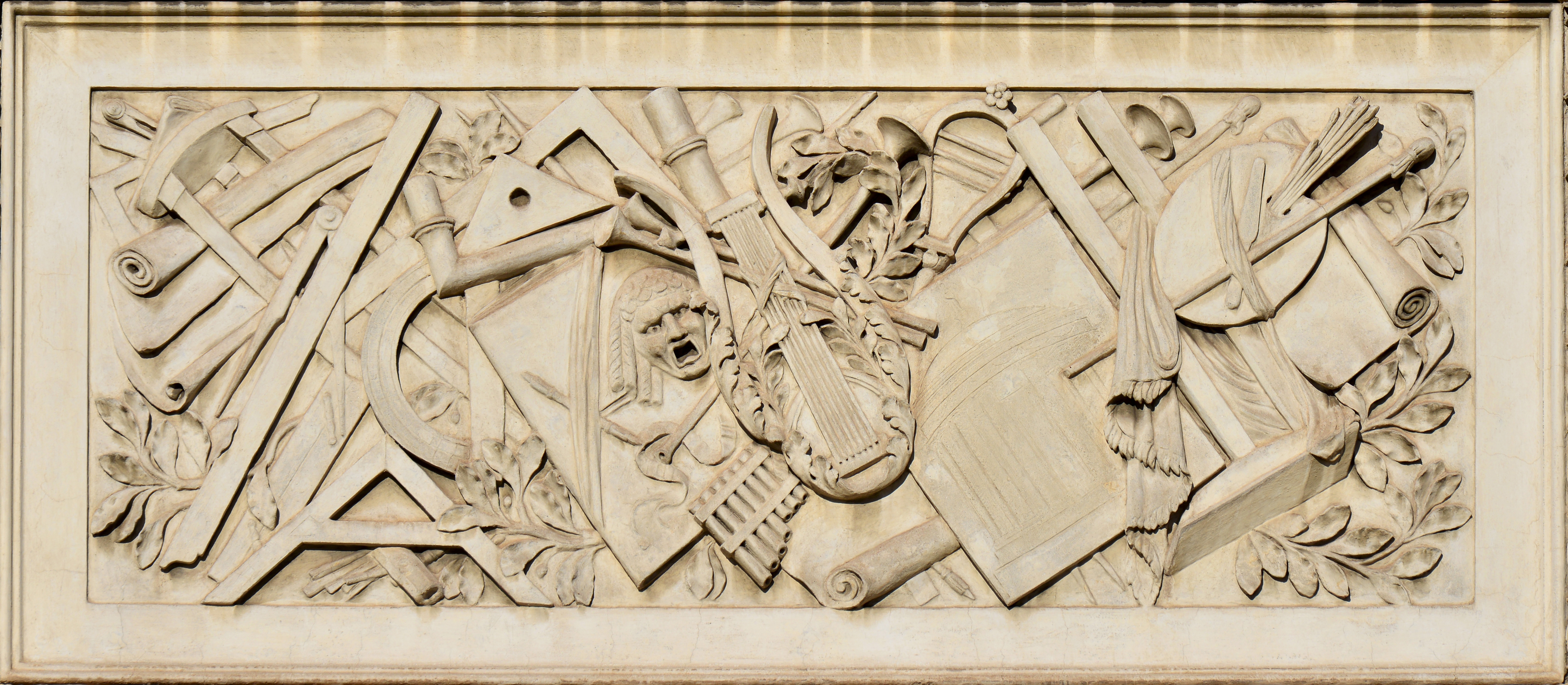 Carved stone relief of instruments and scrolls in classical style, background for direct method Latin