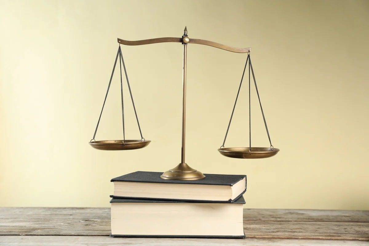 Brass balance scale resting on a stack of old books, an emblem of rendering each his due and of justice in the Bible