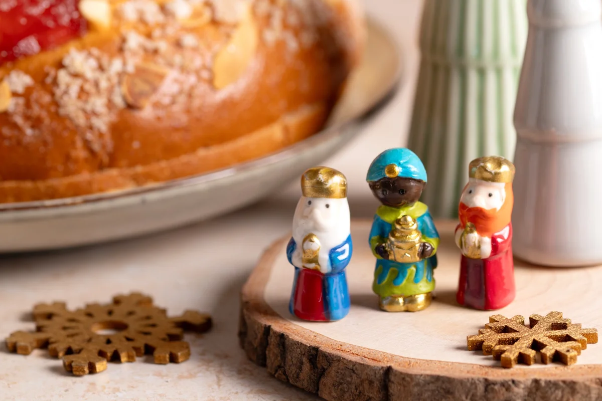 Painted three kings figurines beside a sugared Epiphany bread, a sweet end to the twelve days of Christmas traditions