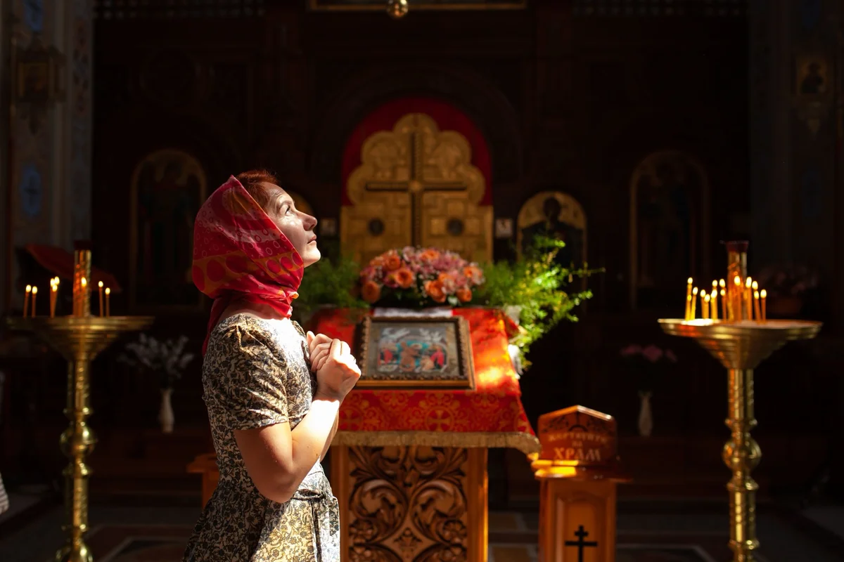 Woman in a red headscarf praying before the altar of an Orthodox church, the inner order that sophrosyne means