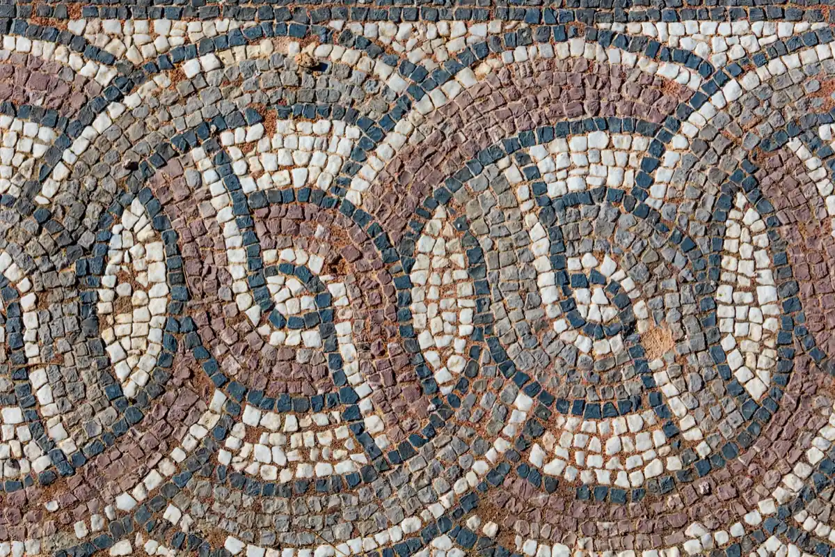 Ancient Roman mosaic of small stone tiles set in interlocking circles, many parts made one whole like unity in Latin