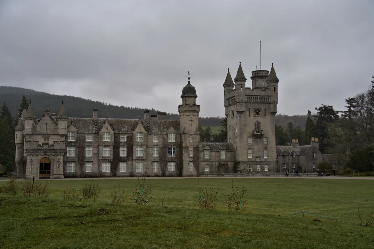 Turreted stone house under a heavy gray sky, the kind of great hall where Jane Eyre and Mr. Rochester meet