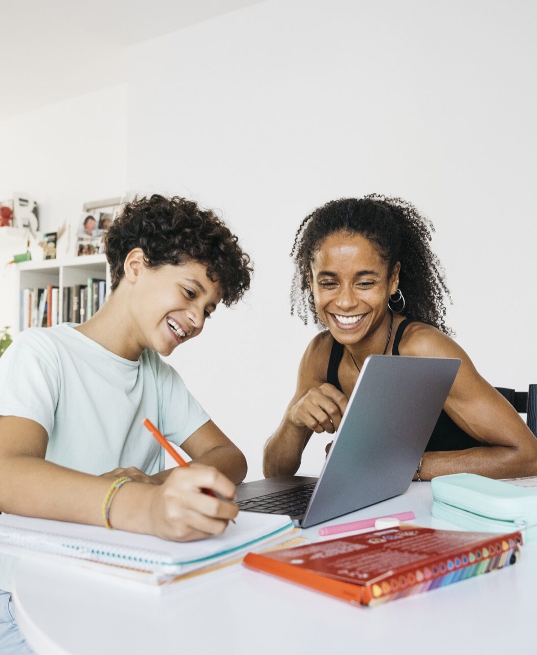 Two smiling students working together at a laptop