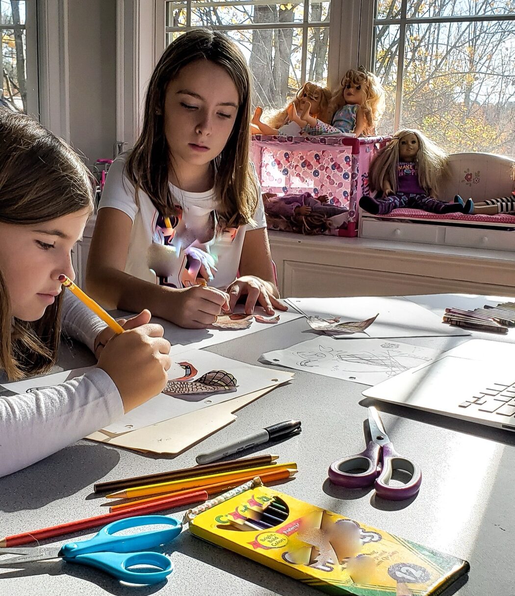 A girl drawing with colored pencils at a table