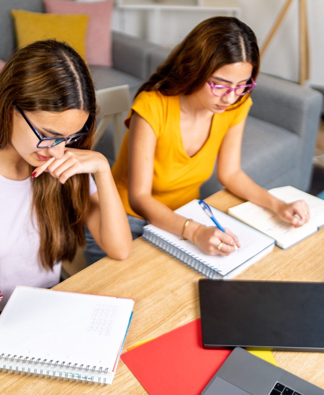 A middle school student writing in a notebook at a desk